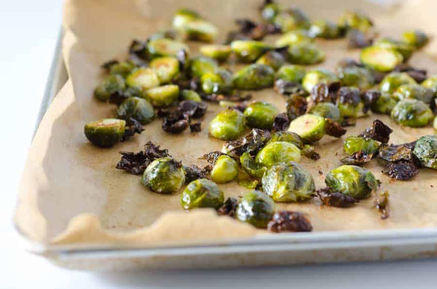 side view of a sheet pan lined with parchment paper and covered in roasted brussel sprouts