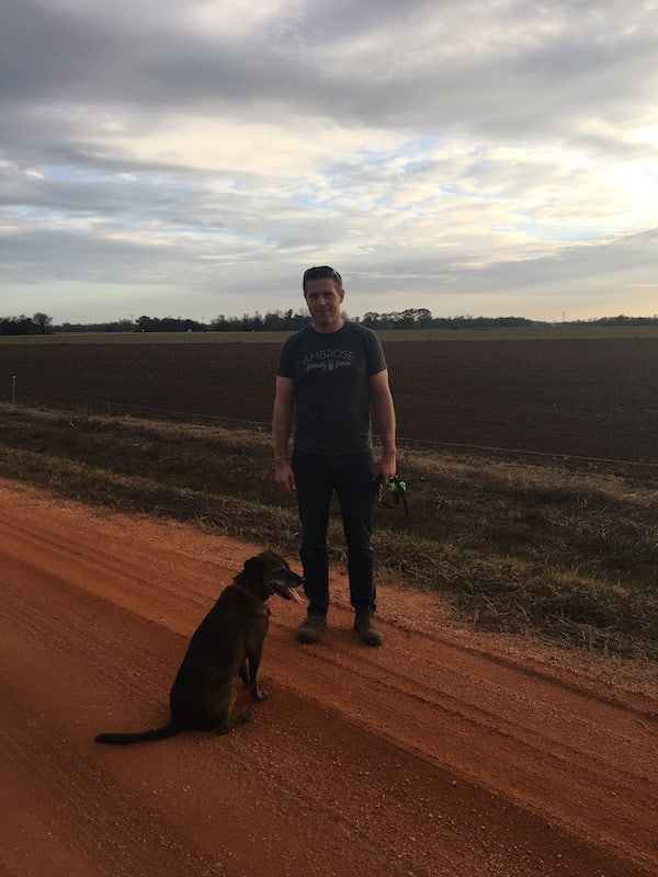 Man and dog standing on dirt road