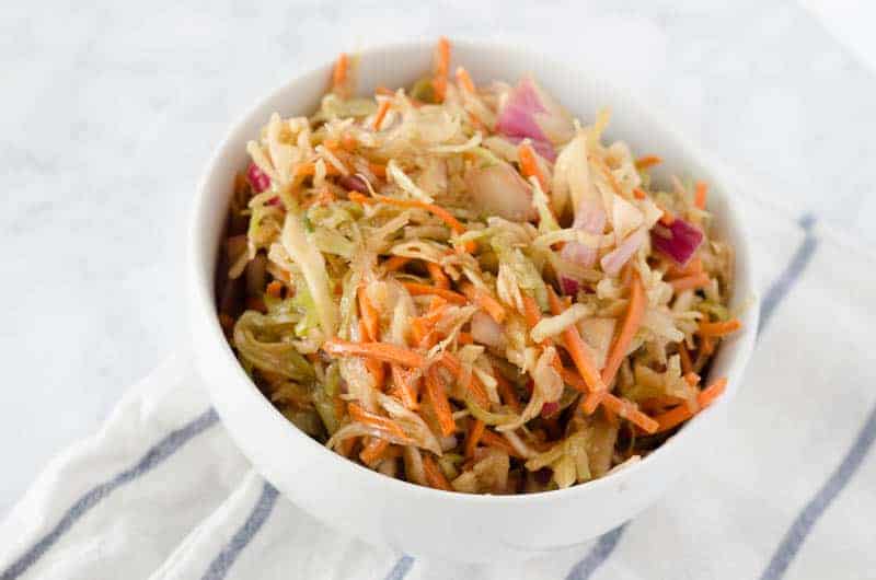 Overhead view of paleo coleslaw in a white bowl on a dish towel