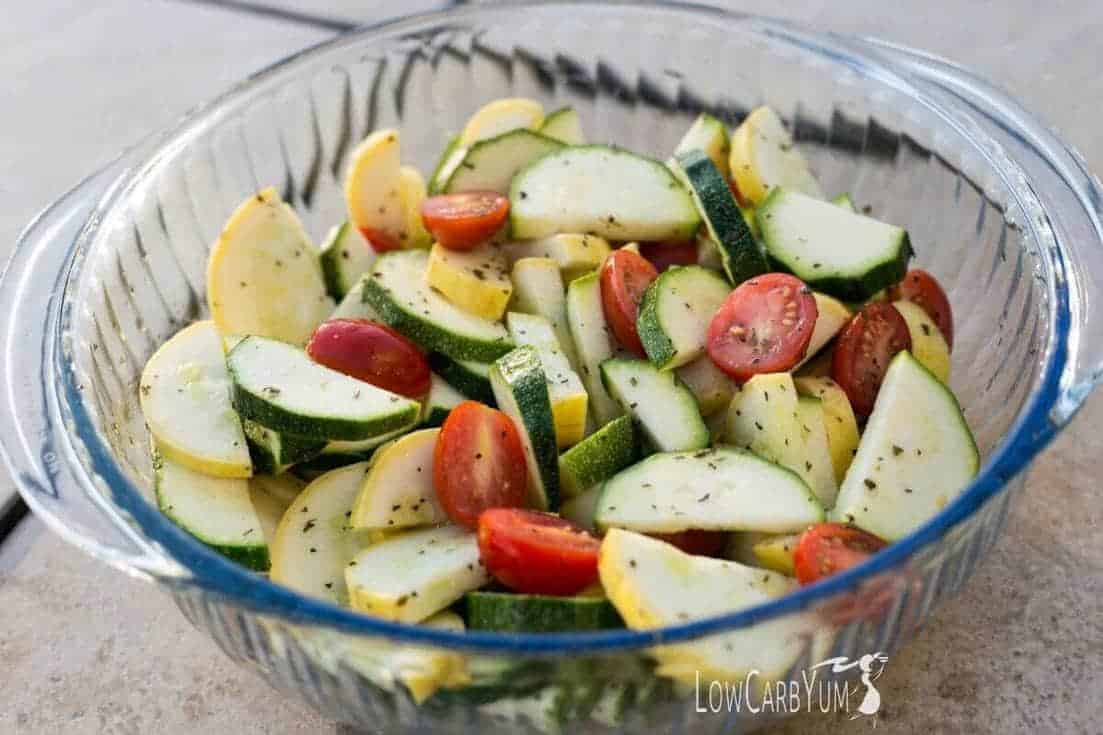 glass serving bowl filled with squash, zucchini, and tomato