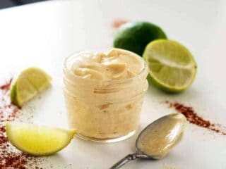 jar of chipotle lime mayo surrounded by chili powder limes and a spoon