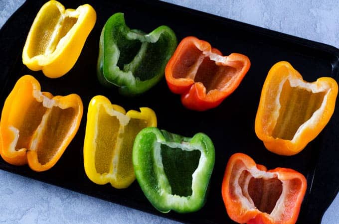 overhead view of a baking sheet with bell peppers cut in half and 