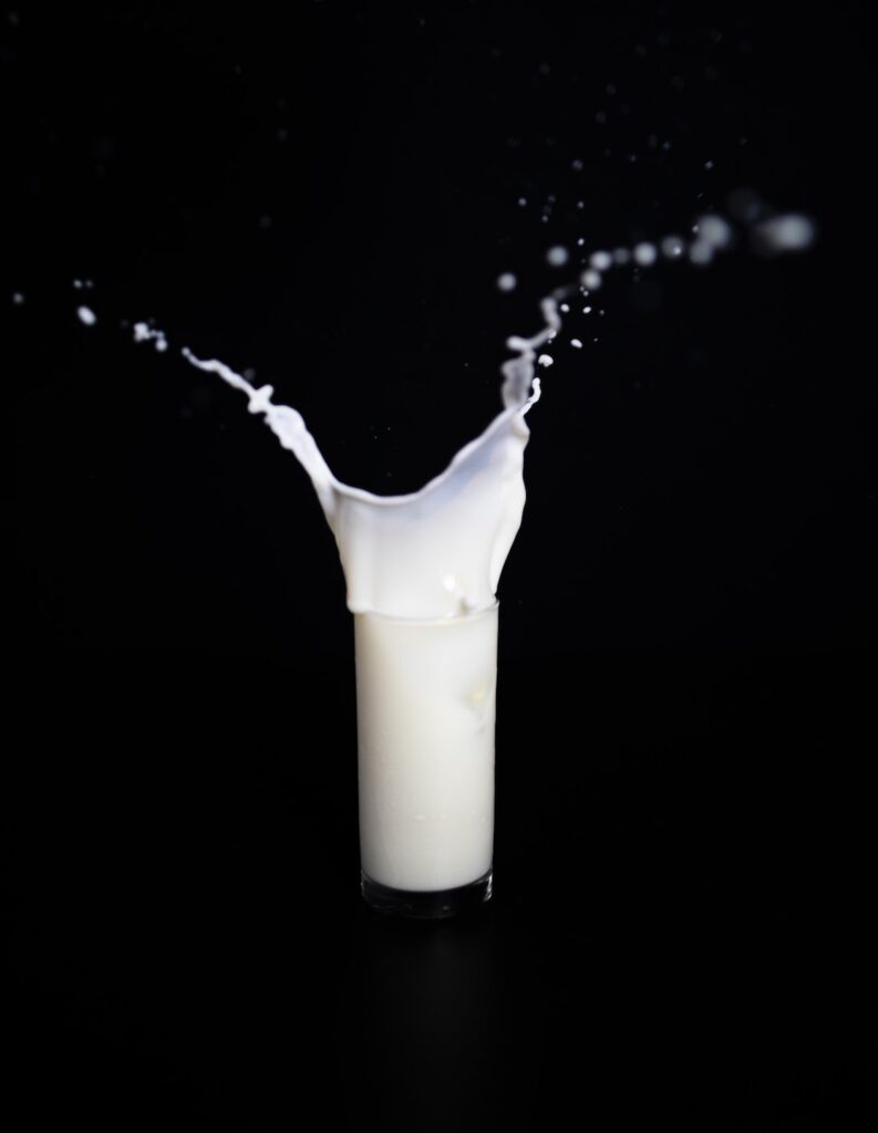 Glass of milk splashing out of glass on black background