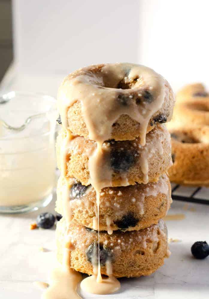 stack of 4 blueberry paleo donuts with glaze dripping down the stack