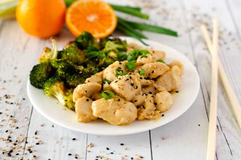 white plate with paleo orange chicken and broccoli with chopsticks next to it