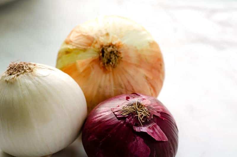 white, yellow, and red onion on a table