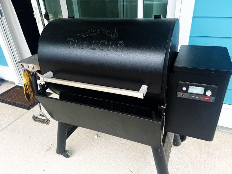 Closed black Traeger grill on a porch with tools hanging off it