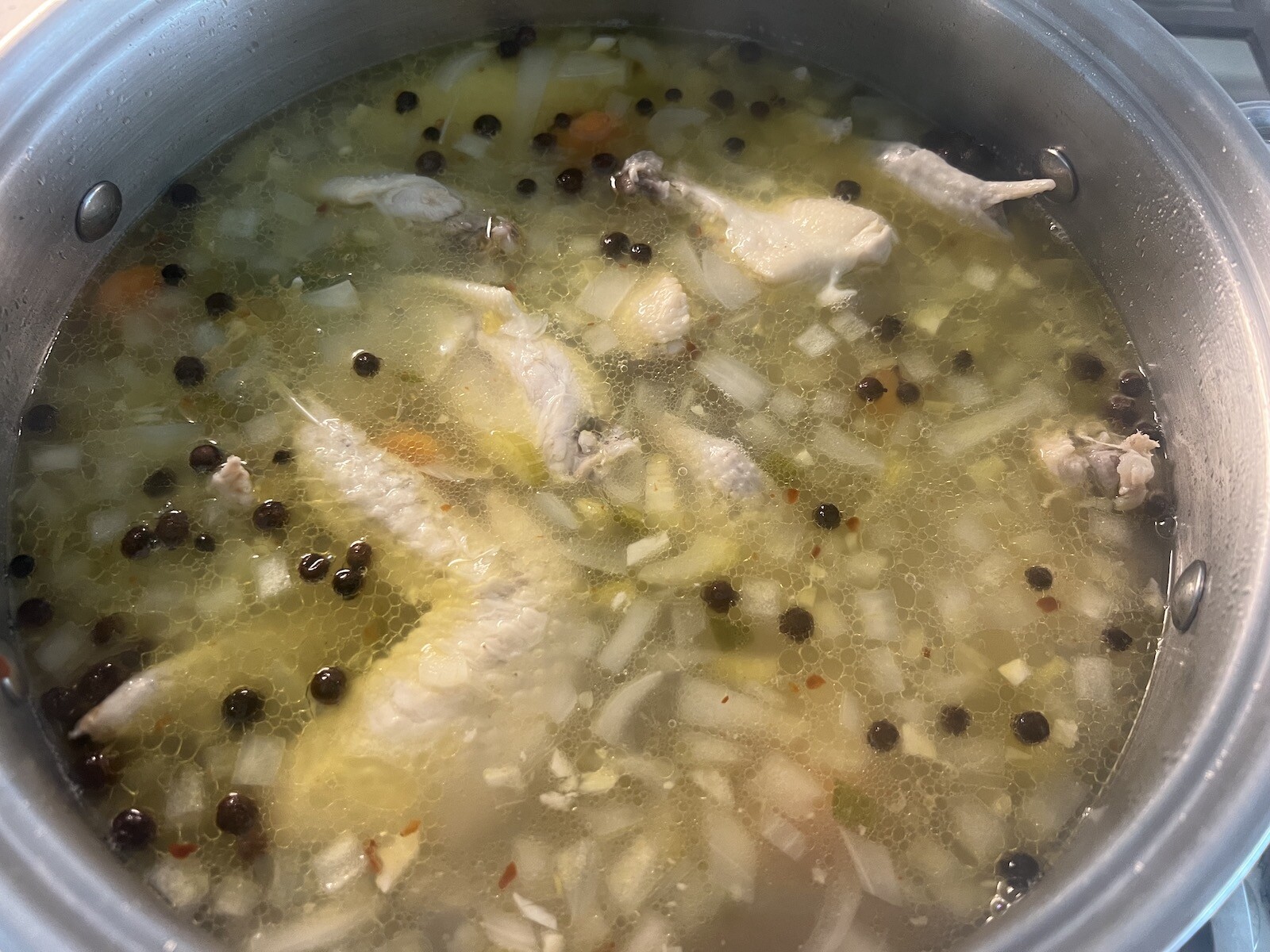 bahamian. chicken souse with allspice cooking in pot