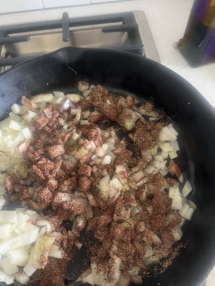 diced onions and dry seasonings cooking in cast iron skillet