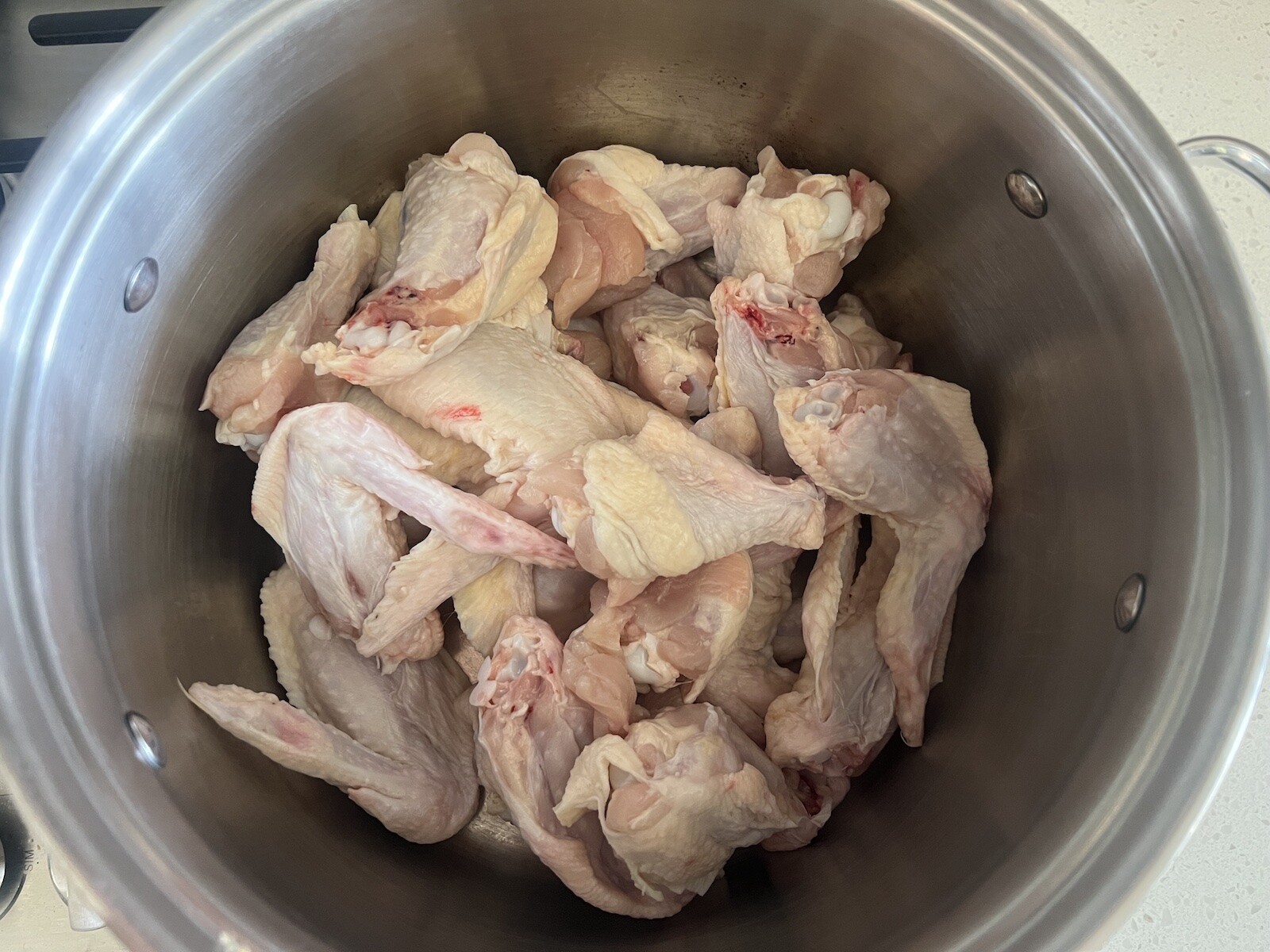 raw chicken wings in stockpot